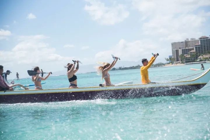 a group of people riding on the back of a boat in the water