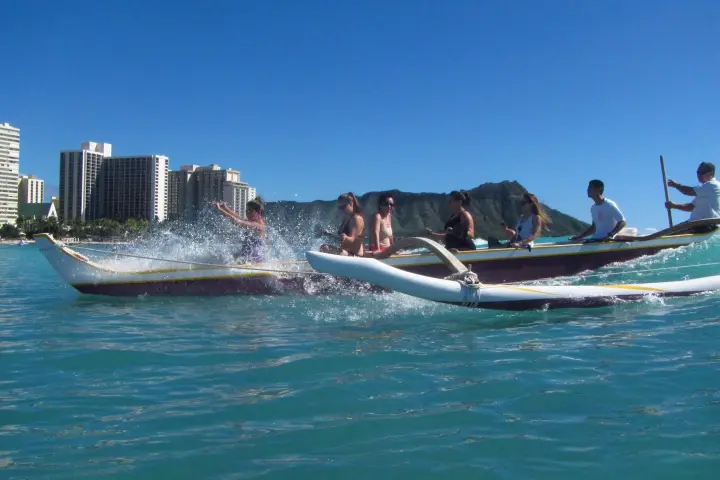 a group of people riding on the back of a boat in the water