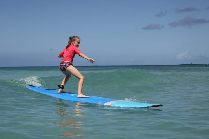 a young girl riding a wave on a surfboard in the water