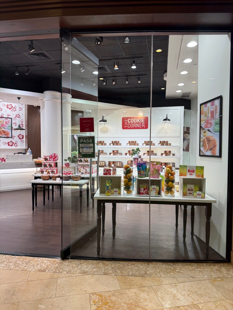 Glass-fronted store with cookies and colorful packaging displayed on tables.