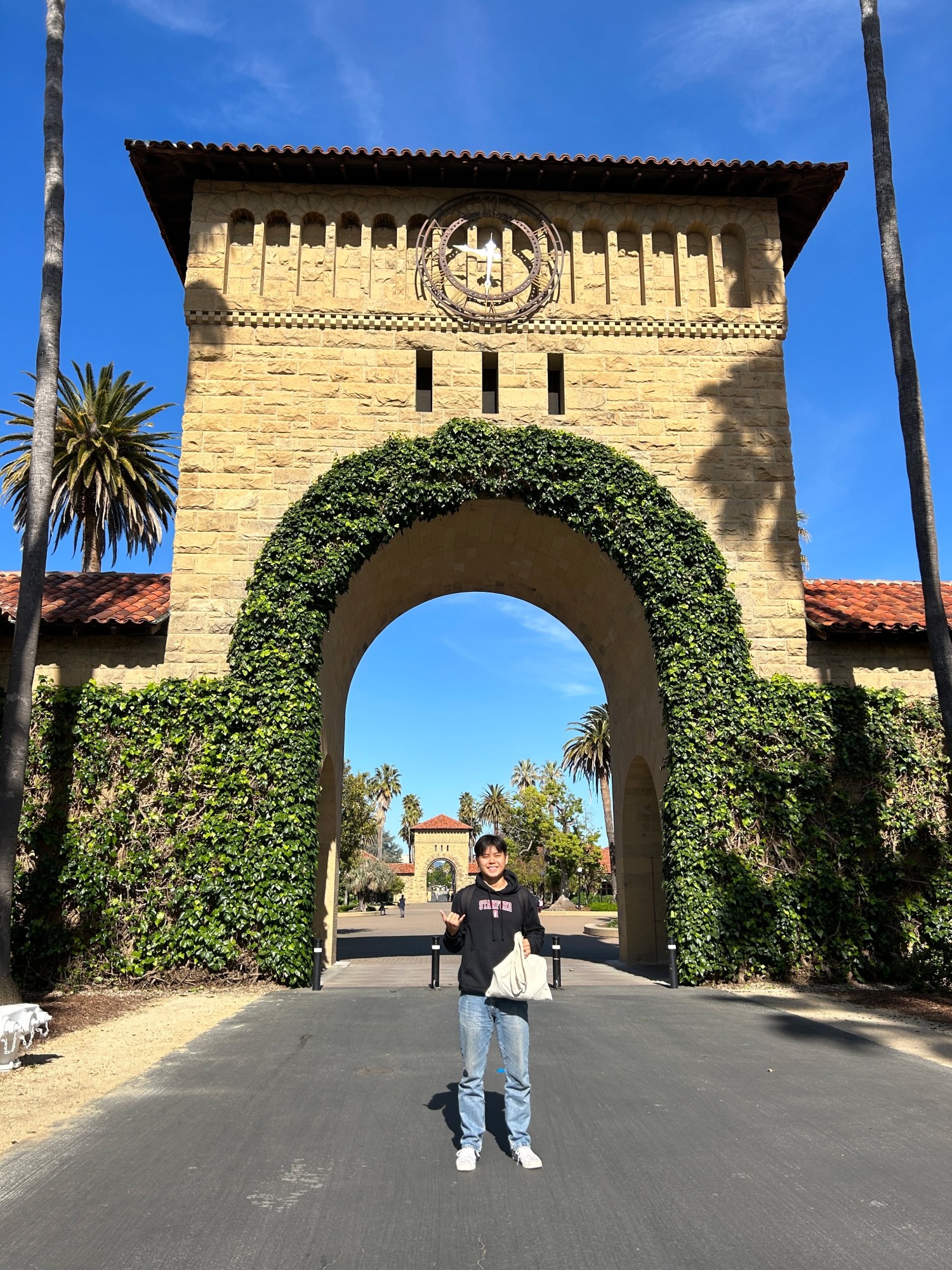 Person standing in front of ivy-covered arch at a historic stone building.