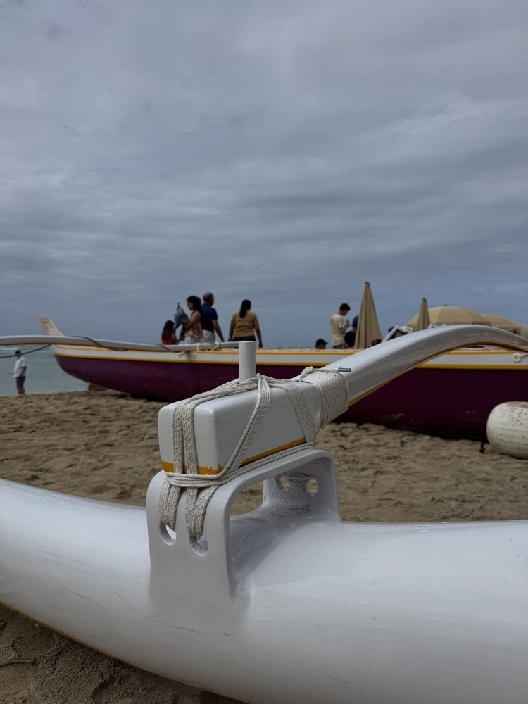 Side view of kayaks on a sandy beach with cloudy sky.