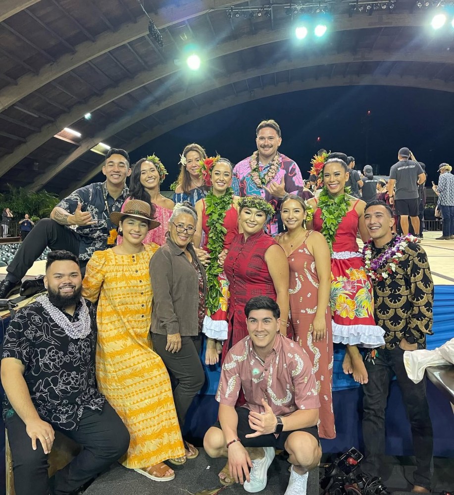 Group of people smiling and posing in colorful outfits on a stage.