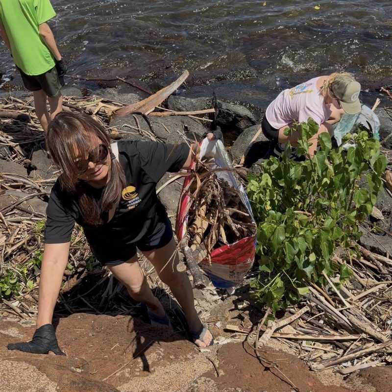 Volunteers clean riverbank, picking up debris and branches.